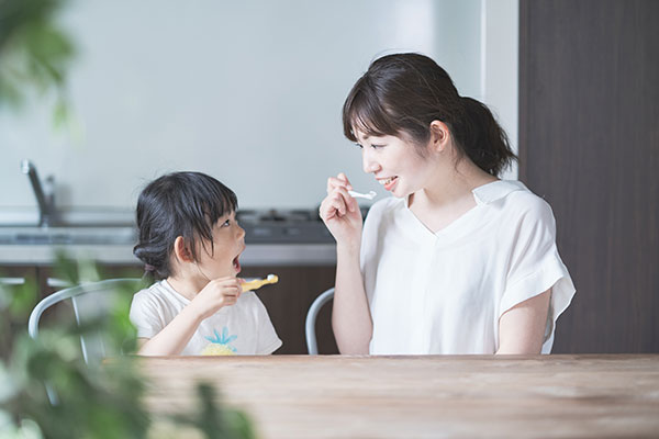 子供が保護者と歯磨きしている写真