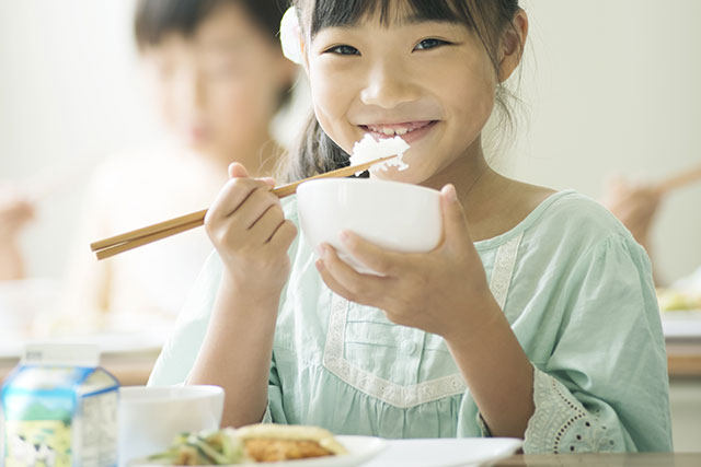 テーブルで食事をする子供の写真